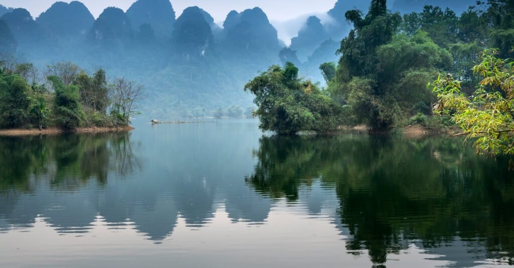 A tranquil river scene with a canoe, misty mountains, and lush greenery, perfect for nature lovers.